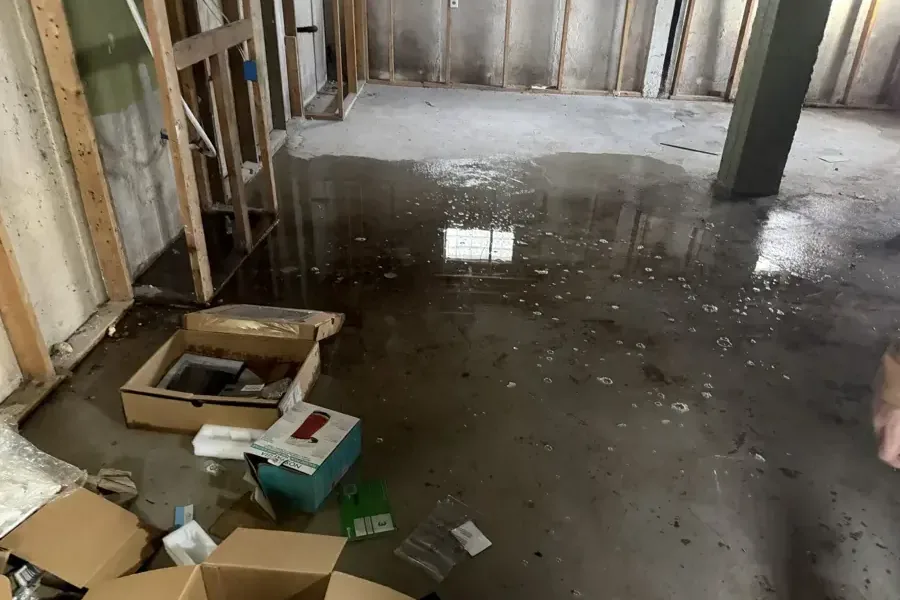 Standing water across a floor beside opened wall framing