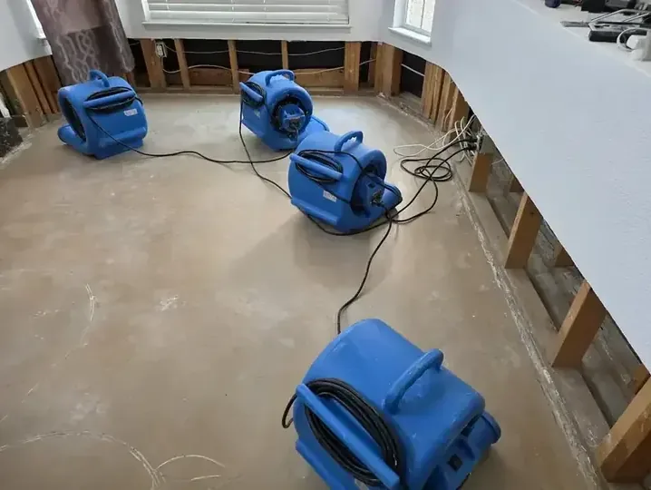 Restoration drying equipment arranged inside a room while wet building materials dry